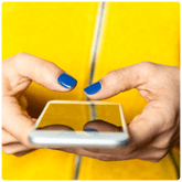 A person in yellow posting on social media on their smartphone.