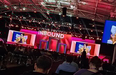 The main stage at Inbound. There are two video screens on the left and right of the interview seat. Above the seats is a sign that says "Inbound." The person being interviewed is Kara Swisher.