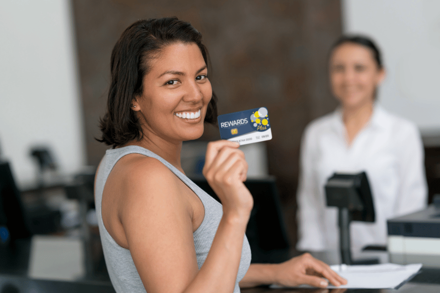 A happy customer showing their customer loyalty rewards card.