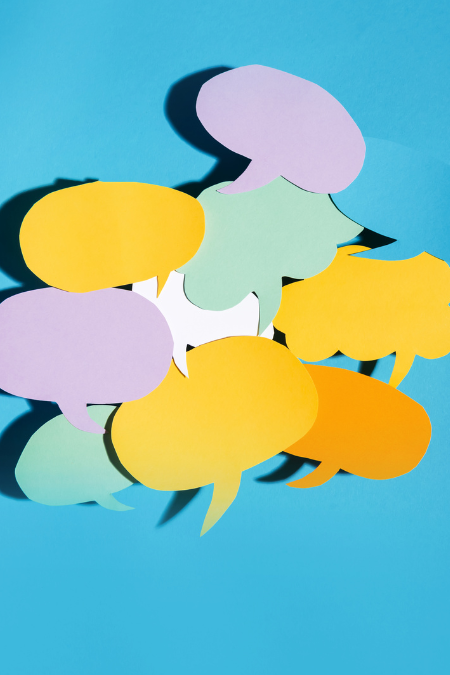 Different color talk bubbles but out of paper sitting on a light blue background.