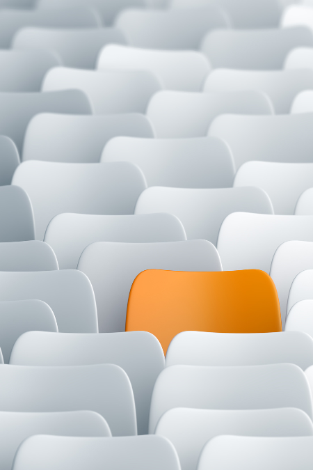 An orange share in a stack of all white chairs.