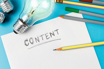 A piece of paper with the word "content" on it. Laying next to is are color pencils and lit up lightbulbs.