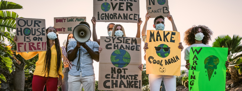 Climate activists holding signs like, "our house is on fire," "system change not climate change," and "no planet b"